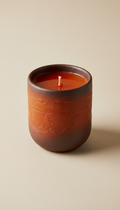 Deep orange soy candle in a ceramic vessel